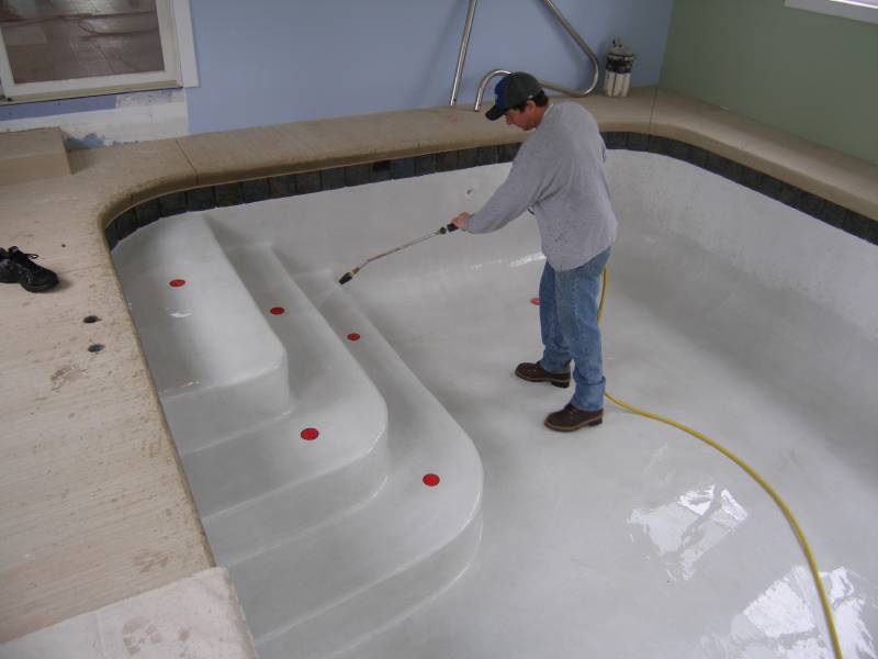 Man Cleaning A Swimming Pool With A Pipe
