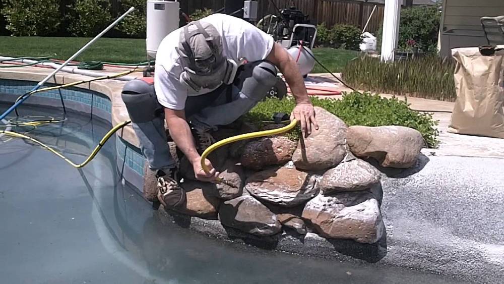 A Man Cleaning Stones Of A Pool With A Pipe