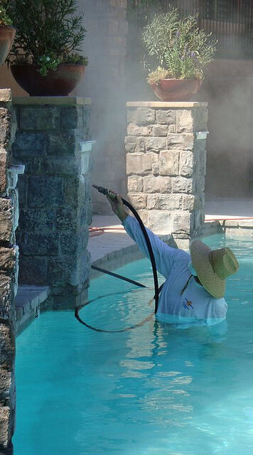 A Man Cleaning A Pool With A Pipe